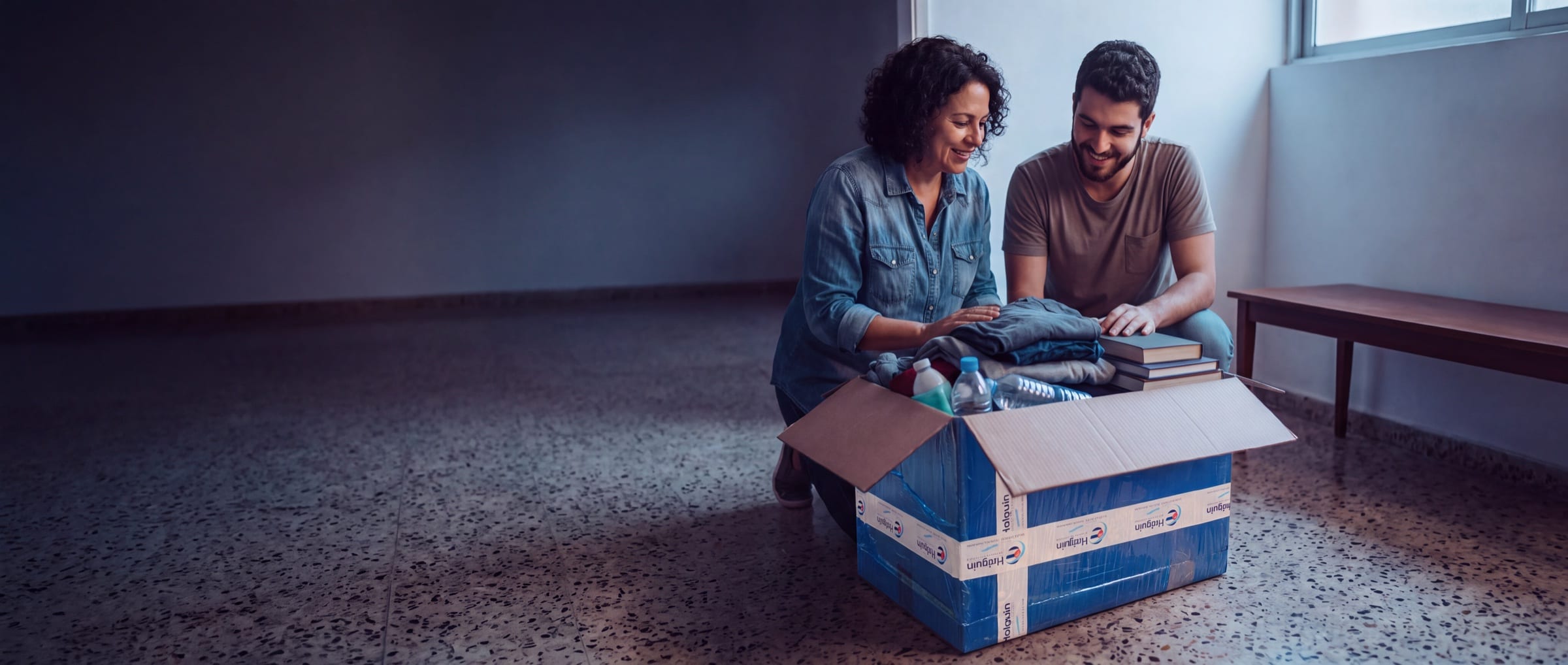 Familia preparando una caja identificada de Holguin Travels para enviarla a Cuba